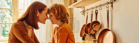 Téléchargez les photos : Vue latérale de mère insouciante et fils souriant face à face près des ustensiles de cuisine dans la cuisine, bannière - en image libre de droit