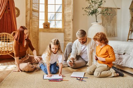 glückliche Eltern und Geschwister, die im modernen Wohnzimmer auf dem Fußboden zusammenziehen, kreative Aktivitäten