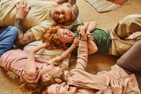 Téléchargez les photos : Vue grand angle des parents et des enfants s'amusant sur le sol dans le salon moderne, moments chéris - en image libre de droit