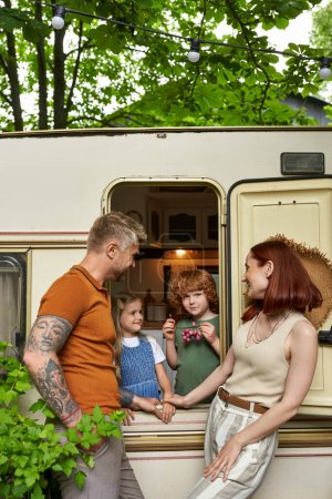 happy parents looking at daughter and son having fun in trailer home, family leisure and recreation