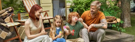 Téléchargez les photos : Parents souriants regardant des enfants souffler des bulles de savon près de la maison de remorque, loisirs et plaisir, bannière - en image libre de droit