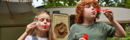 Photo for Adorable children blowing soap bubbles near trailer home outdoors, siblings playing together, banner - Royalty Free Image