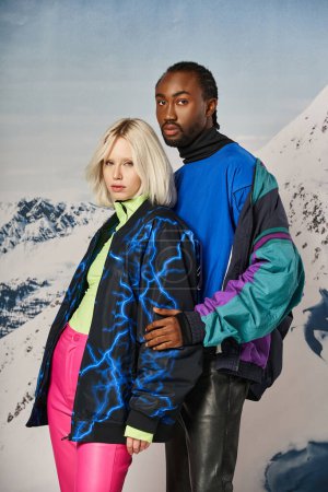 attraktives junges multikulturelles Paar in stylischer Winterkleidung umarmt und posiert vor verschneiter Kulisse