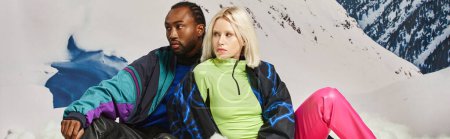 beau couple multiculturel dans des tenues chaudes et lumineuses avec toile de fond de montagne, concept d'hiver, bannière