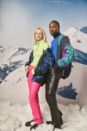 schönes multikulturelles Paar in trendigen, lebendigen Klamotten, die gemeinsam vor der Kamera posieren, Winterkonzept