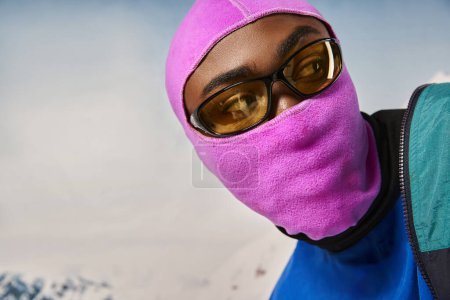 Téléchargez les photos : Portrait de jeune homme afro-américain en cagoule vibrante rose regardant ailleurs, concept d'hiver - en image libre de droit