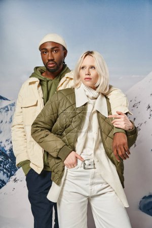 attraktives stylisches Paar in saisonalen Outfits posiert vor Bergkulisse, Winterkonzept