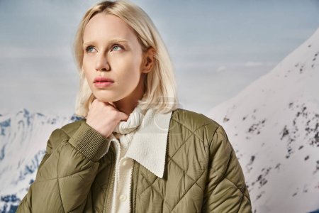 beautiful blonde woman in khaki jacket posing with her hand on chin and looking away, winter fashion