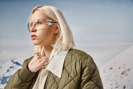 beautiful blonde woman in modish glasses wearing warm jacket and looking away, winter fashion