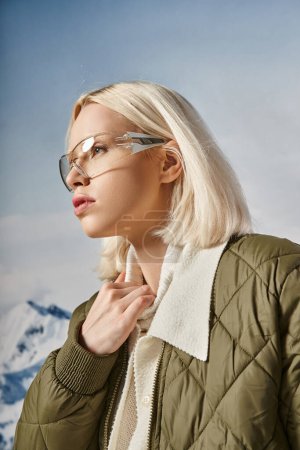 mujer atractiva con elegante atuendo cálido con gafas y mirando hacia otro lado, mano sobre cuello, moda