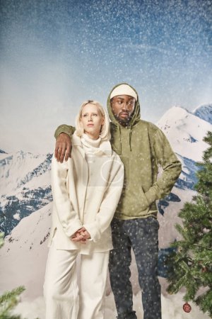 Téléchargez les photos : Bel homme en veste élégante mettant son bras sur son épaule de petite amie sous la neige, hiver - en image libre de droit