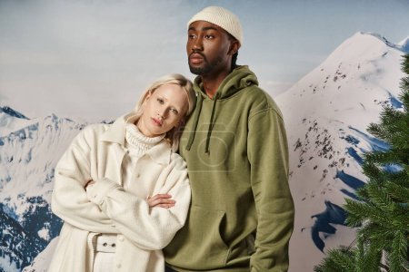 stylish blonde woman with her head on her boyfriend chest posing on snowy backdrop, winter concept