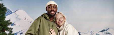 Banner der glücklichen Frau, die sich mit ihrem afrikanisch-amerikanischen Freund vor Bergkulisse umarmt, Wintermode