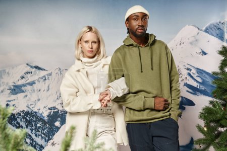 stylische blonde Frau mit afrikanisch-amerikanischem Freund vor Bergkulisse, Wintermode