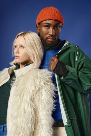 pareja multiétnica posando en traje de invierno con la montaña en el telón de fondo, hombre y mujer afroamericanos