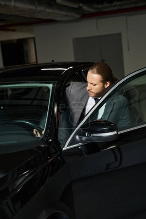 Foto de Hombre elegante guapo con cola de caballo en traje elegante elegante entrar en su coche, concepto de negocio - Imagen libre de derechos