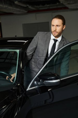 Foto de Profesional de buen aspecto en elegante traje inteligente entrar en su coche en el estacionamiento, negocio - Imagen libre de derechos