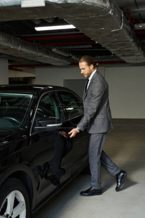 Foto de Atractivo hombre de pelo rojo en traje inteligente entrar en su coche en el estacionamiento, concepto de negocio - Imagen libre de derechos