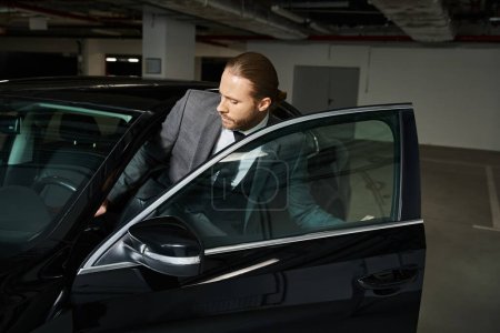 attractive elegant man in chic smart suit getting into his car on parking lot, business concept
