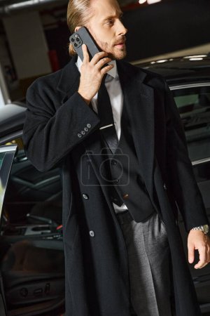 handsome elegant man with ponytail and tie talking by phone on parking lot, business concept