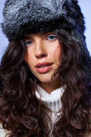 Téléchargez les photos : Belle jeune femme en chapeau fourrure et tenue blanche posant sur fond gris, mode d'hiver - en image libre de droit