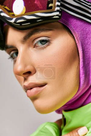 Téléchargez les photos : Gros plan de la femme en vêtements de ski d'hiver avec cagoule sur la tête regardant caméra sur gris, portrait - en image libre de droit