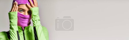 Photo for Banner of sportive woman with blue eyes wearing purple ski mask and looking at camera on grey - Royalty Free Image