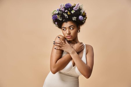 retrato de encantadora mujer afroamericana con flores de colores en el pelo mirando hacia otro lado en beige