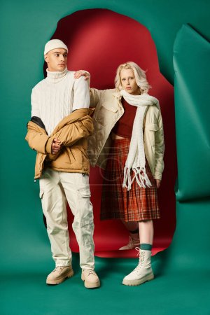 Foto de Longitud completa de la pareja con estilo en chaquetas de invierno posando juntos en rojo con fondo turquesa - Imagen libre de derechos