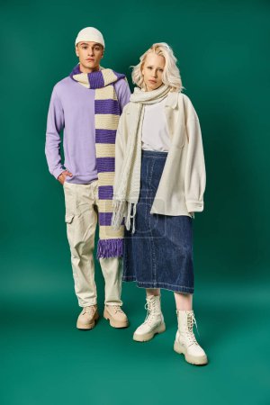 Foto de Colores de moda, hombre en bufanda desnuda y gorro posando con hermosa mujer sobre fondo turquesa - Imagen libre de derechos