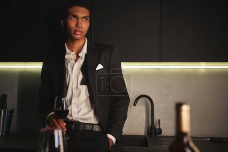 Photo for Handsome african american man with pierced nose in chic suit posing with glass of red wine - Royalty Free Image
