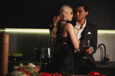 Téléchargez les photos : Jeune couple interracial dans des tenues élégantes de soirée posant ensemble et se préparant à embrasser avec amour - en image libre de droit