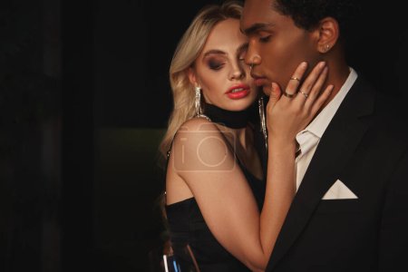 attraktive junge multikulturelle Paar in eleganten Abendkleidern posiert verführerisch zusammen