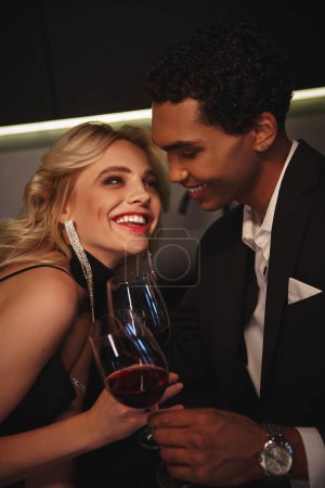 Téléchargez les photos : Gai attrayant interracial couple dans chic vêtements cliquetis lunettes et sourire heureux - en image libre de droit