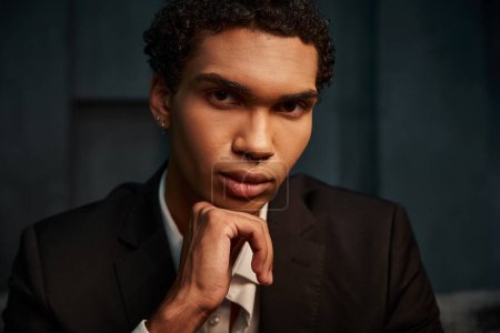 atractivo modelo masculino afroamericano de buen aspecto en traje elegante posando y mirando a la cámara
