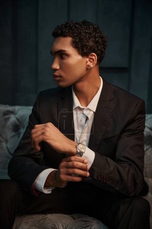 atractivo joven afroamericano modelo masculino en traje elegante con accesorios posando y mirando hacia otro lado