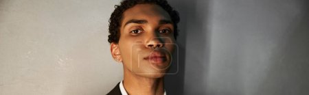 jeune bel homme afro-américain en costume élégant avec perçage regardant la caméra, bannière