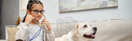 glückliches Mädchen in Freizeitkleidung und Brille spielender Arzt mit Labrador-Hund im Wohnzimmer, Banner