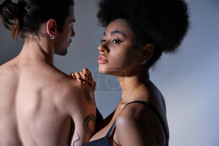 Téléchargez les photos : Jeune homme posant avec sa belle petite amie en soutien-gorge noir sur fond gris, couple sexy - en image libre de droit