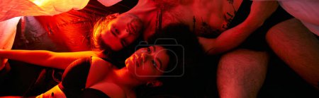 attractive diverse couple lying sensually together under bedsheet surrounded by lights, banner