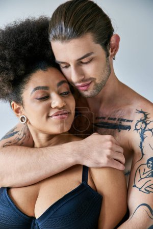 Foto de Atractivo joven novio multicultural y novia en ropa interior abrazándose calurosamente, juntos - Imagen libre de derechos