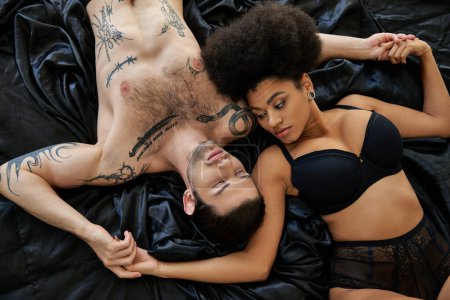 Téléchargez les photos : Belle femme afro-américaine en sous-vêtements couchée dans le lit à côté de son petit ami, couple sexy - en image libre de droit