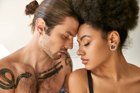Téléchargez les photos : Beau couple multiracial en sous-vêtements posant sensuellement et amoureusement dans leur chambre - en image libre de droit