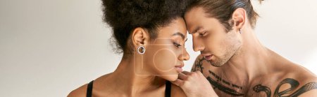 Téléchargez les photos : Attrayant couple multiracial en sous-vêtements posant sensuellement et amoureusement dans leur chambre, bannière - en image libre de droit