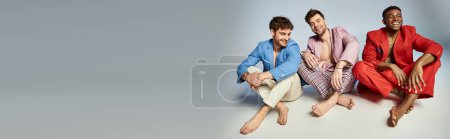 Photo for Cheerful diverse men in bright suits sitting on floor with crossed legs and smiling joyfully, banner - Royalty Free Image