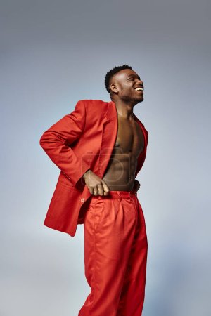 junge afrikanisch-amerikanische männliche Modell mit lebendigen dapper Stil posiert auf grauem Hintergrund, Modekonzept