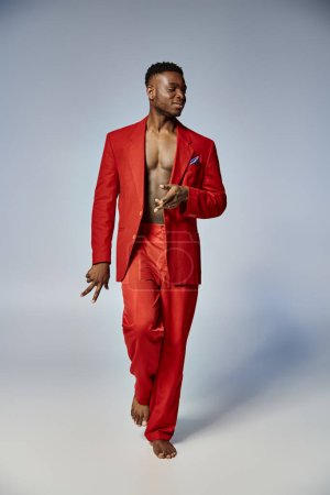 Foto de Modelo masculino afroamericano de moda con estilo elegante posando sobre fondo gris, concepto de moda - Imagen libre de derechos