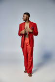 handsome african american man in stylish red suit posing on gray backdrop, fashion concept Stickers #685858388