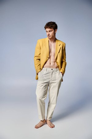 atractivo hombre con estilo en chaqueta amarilla posando atractivamente sobre fondo gris, concepto de moda