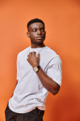 good looking african american man in street casual outfit on orange backdrop, fashion concept puzzle #685858840
